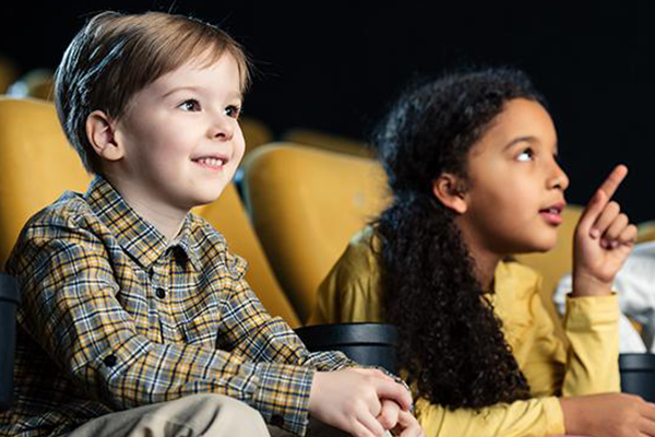 Foto af to børn, der peger, mens de ser film sammen